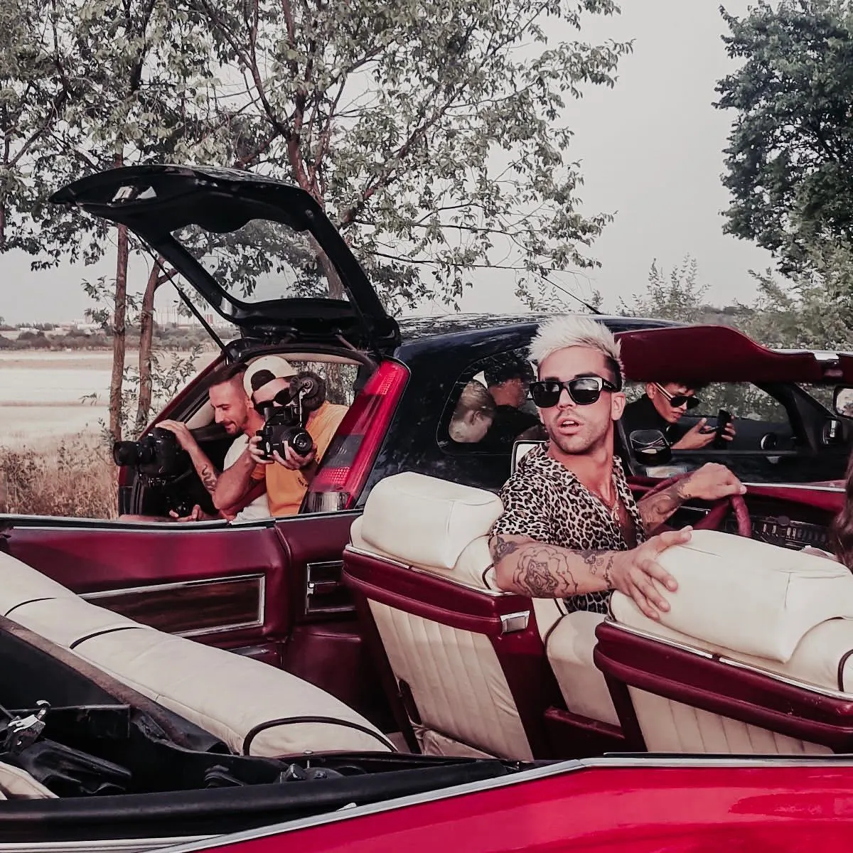 Artist in the back seat of a vintage red convertible