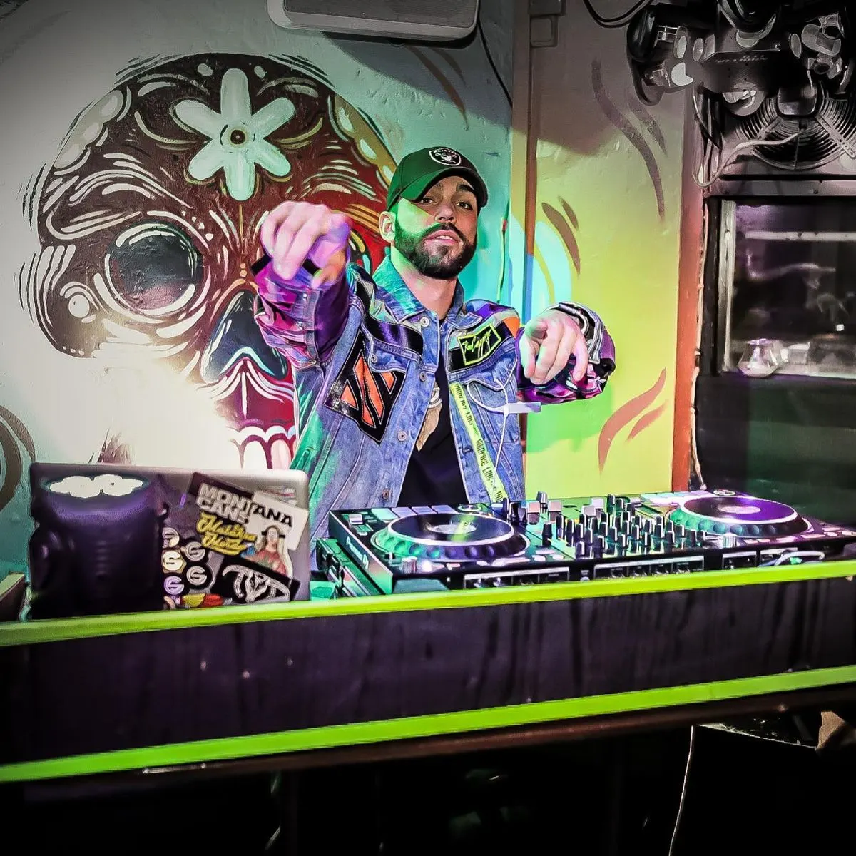 DJ playing in front of a painted skull mural