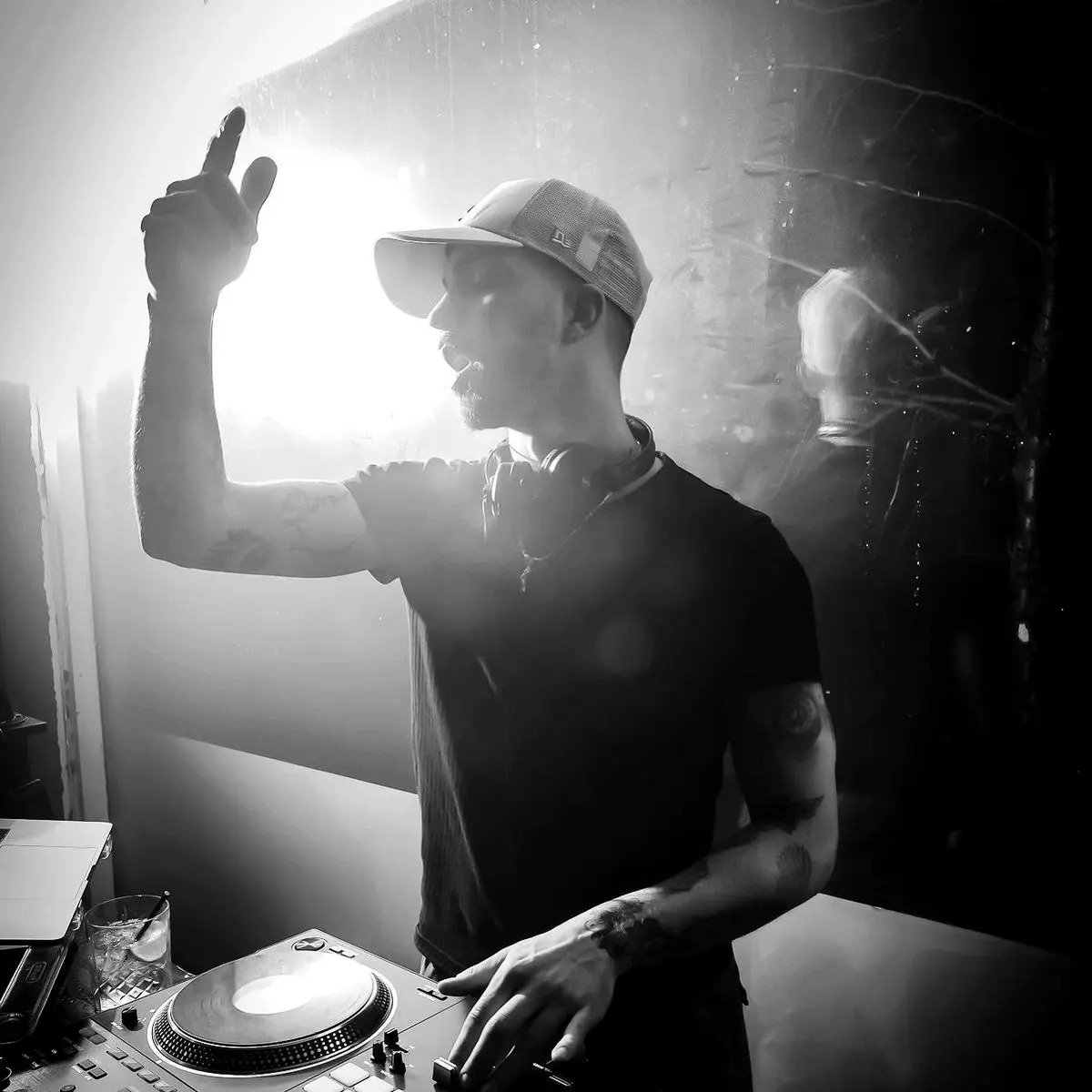 DJ raising a hand behind the decks