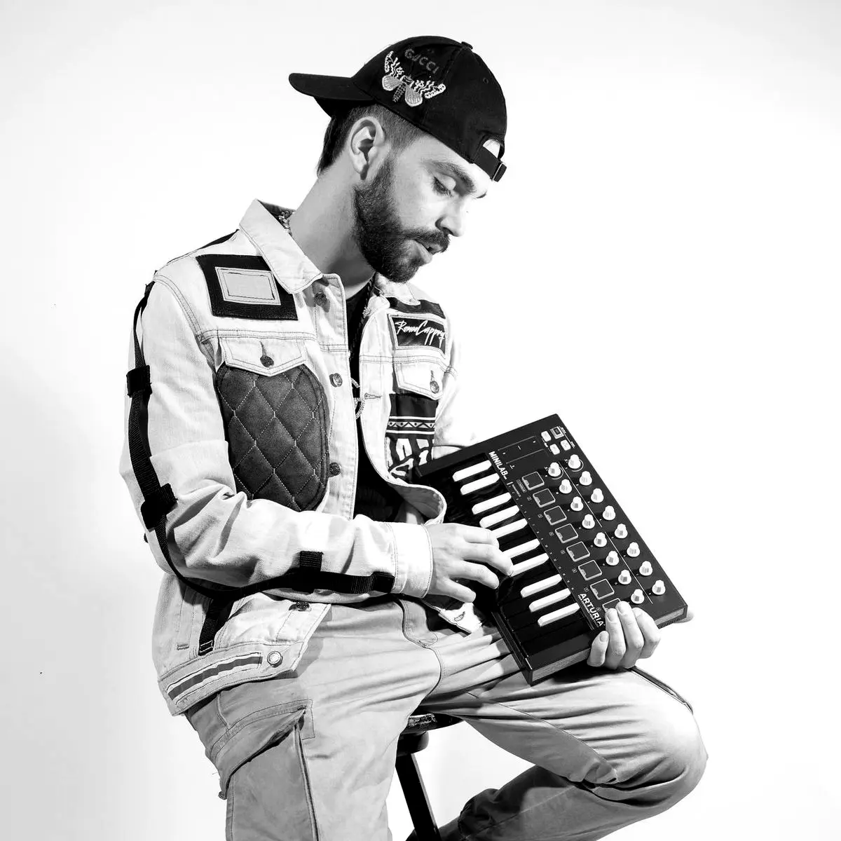Producer holding a MIDI keyboard against a white wall