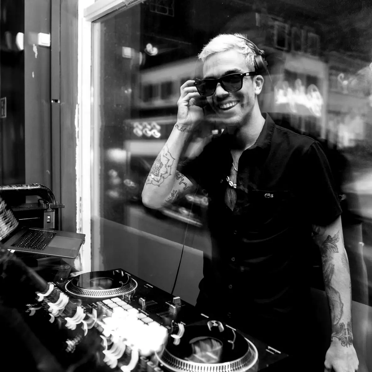 Tattooed DJ smiling behind the decks at night