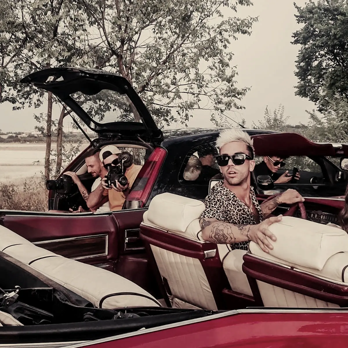 Artist in the back seat of a vintage red convertible